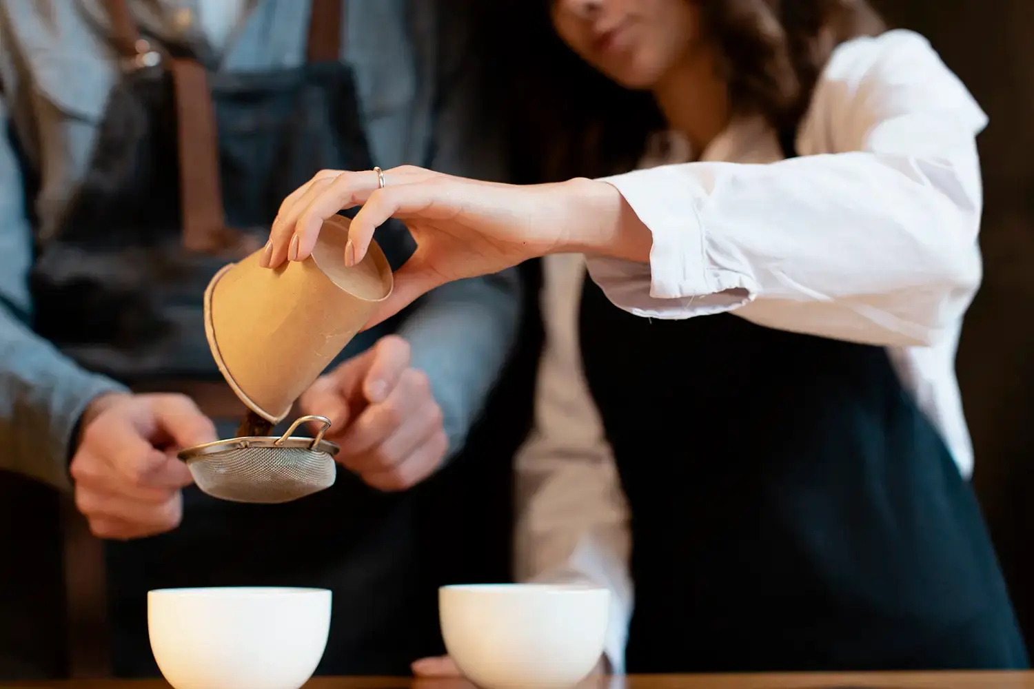 Personne versant du thé en vrac dans un infuseur métallique au-dessus d’une tasse pour préparation artisanale